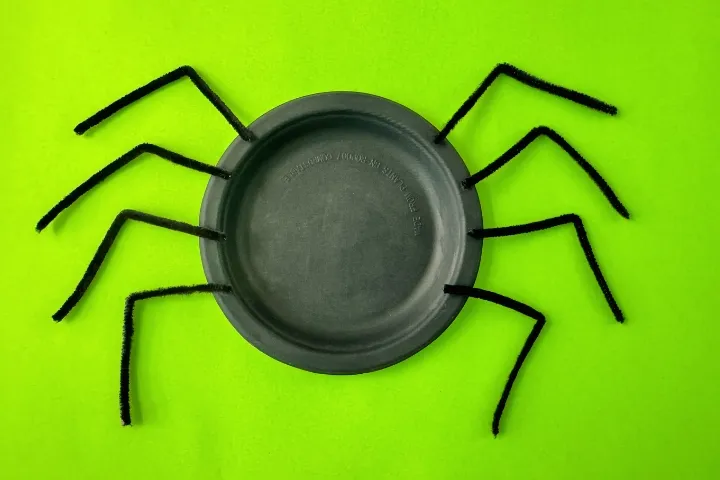 Fun preschool paper plate spider craft for Halloween, made with googly eyes and pipe cleaner legs.