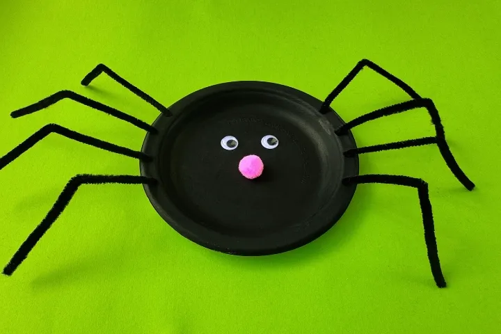 Fun preschool paper plate spider craft for Halloween, made with googly eyes and pipe cleaner legs.