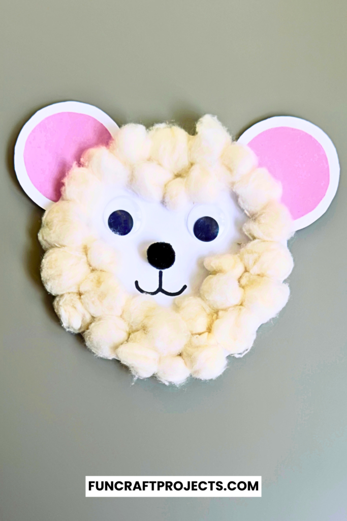 A cute cotton ball polar bear craft, white paper, and black and orange construction paper details.