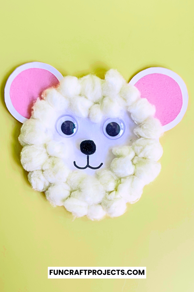 A cute cotton ball polar bear craft, white paper, and black and orange construction paper details.