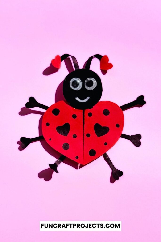 Heart Shaped Ladybug Craft made with red and black construction paper, googly eyes, and heart-shaped wings is a fun Valentine’s Day craft for kids.