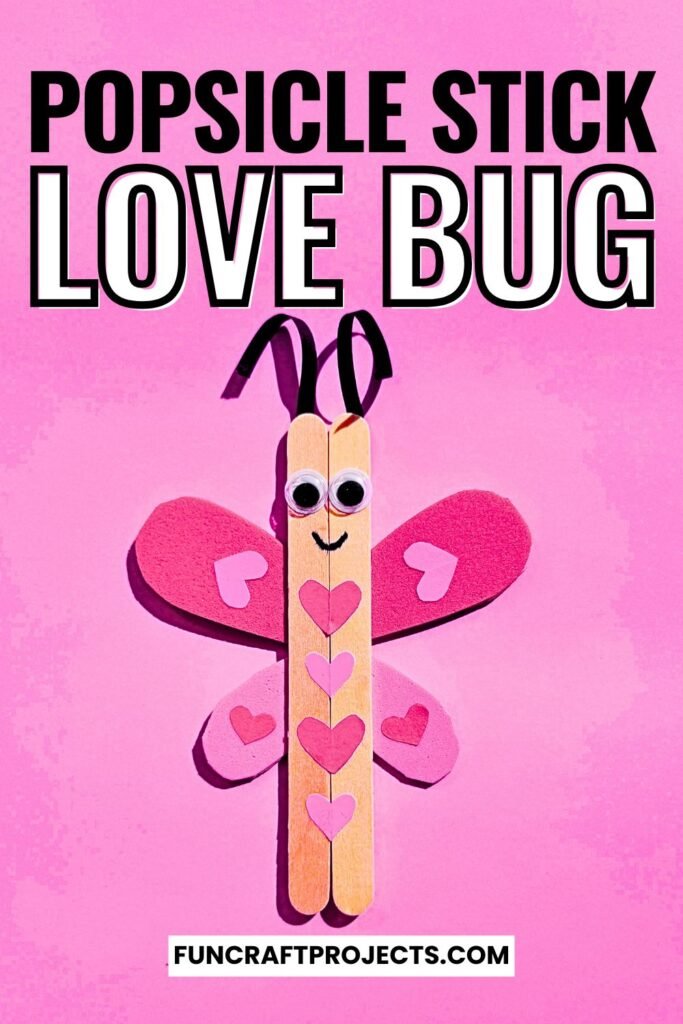 A cute Popsicle Stick Love Bug Craft made with wooden craft sticks, red and pink heart-shaped wings, and googly eyes, displayed on a blue background.